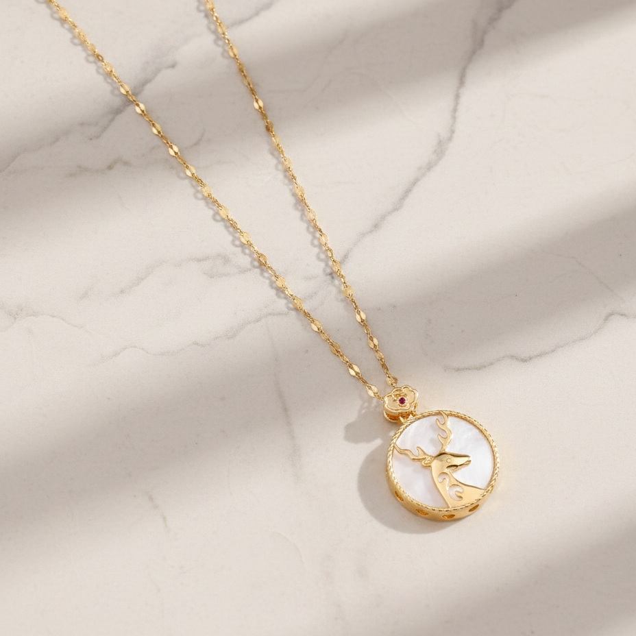 Gold necklace with a round pendant on a marble surface